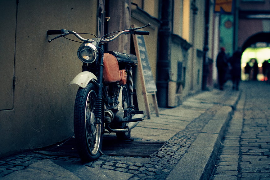 Vintage motorcycle parked on cobblestone street in European city