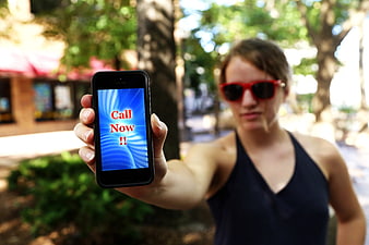 Woman holding smartphone with call now screen outdoors