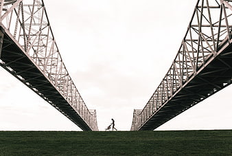 Woman pushing stroller under large steel bridge structure