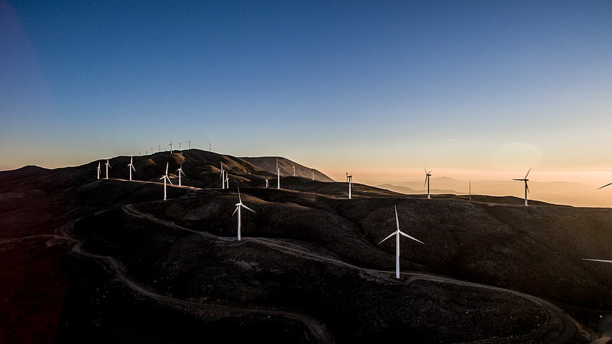 Wind turbines on rolling hills at sunset