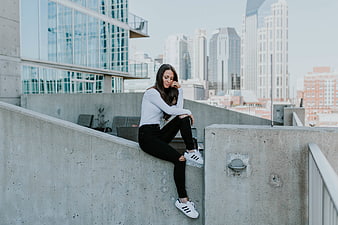Woman sitting on concrete wall with city skyline background