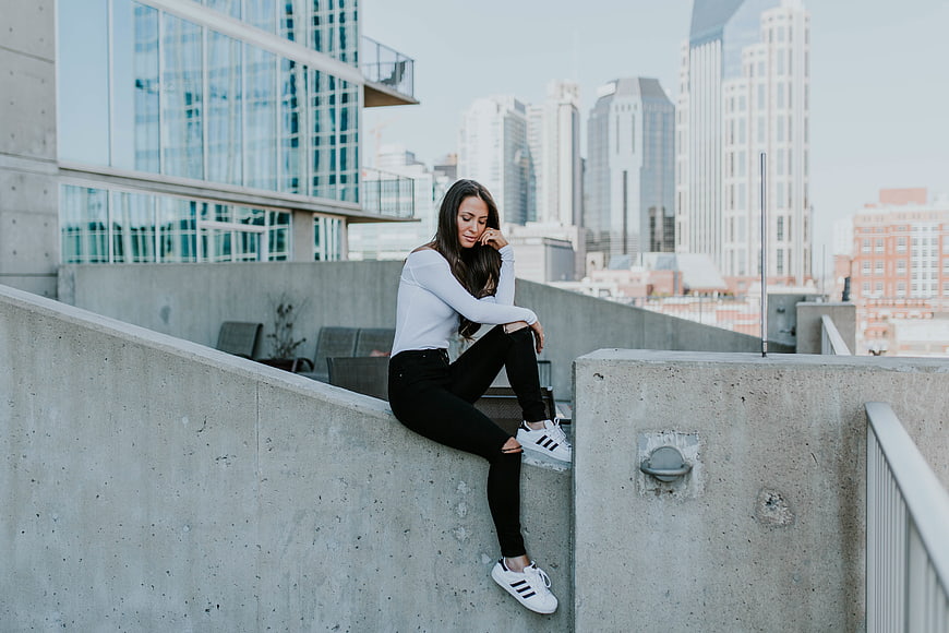 Woman sitting on concrete wall with city skyline background