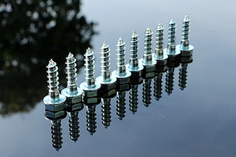 Row of silver screws with reflections on black surface