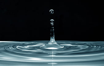 Water droplet splash with ripples on dark background