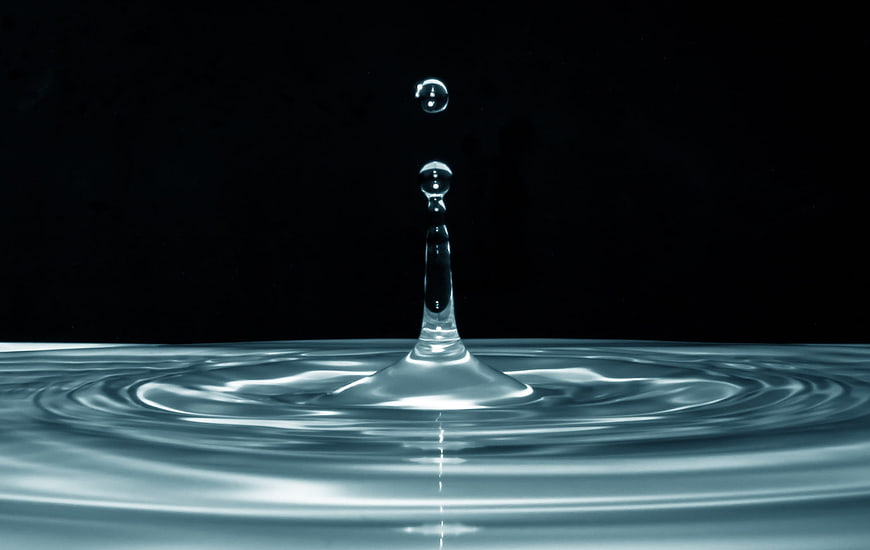 Water droplet splash with ripples on dark background