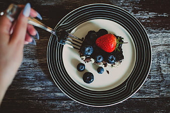Overhead view of chocolate cake with berries on striped plate