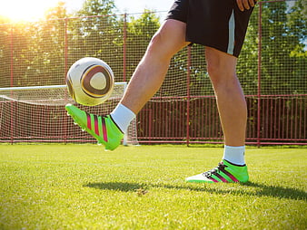 Soccer Player Kicking Ball On Green Grass Field