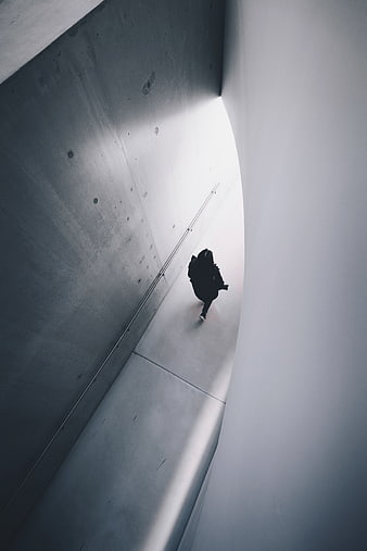 Silhouette of person walking in concrete tunnel