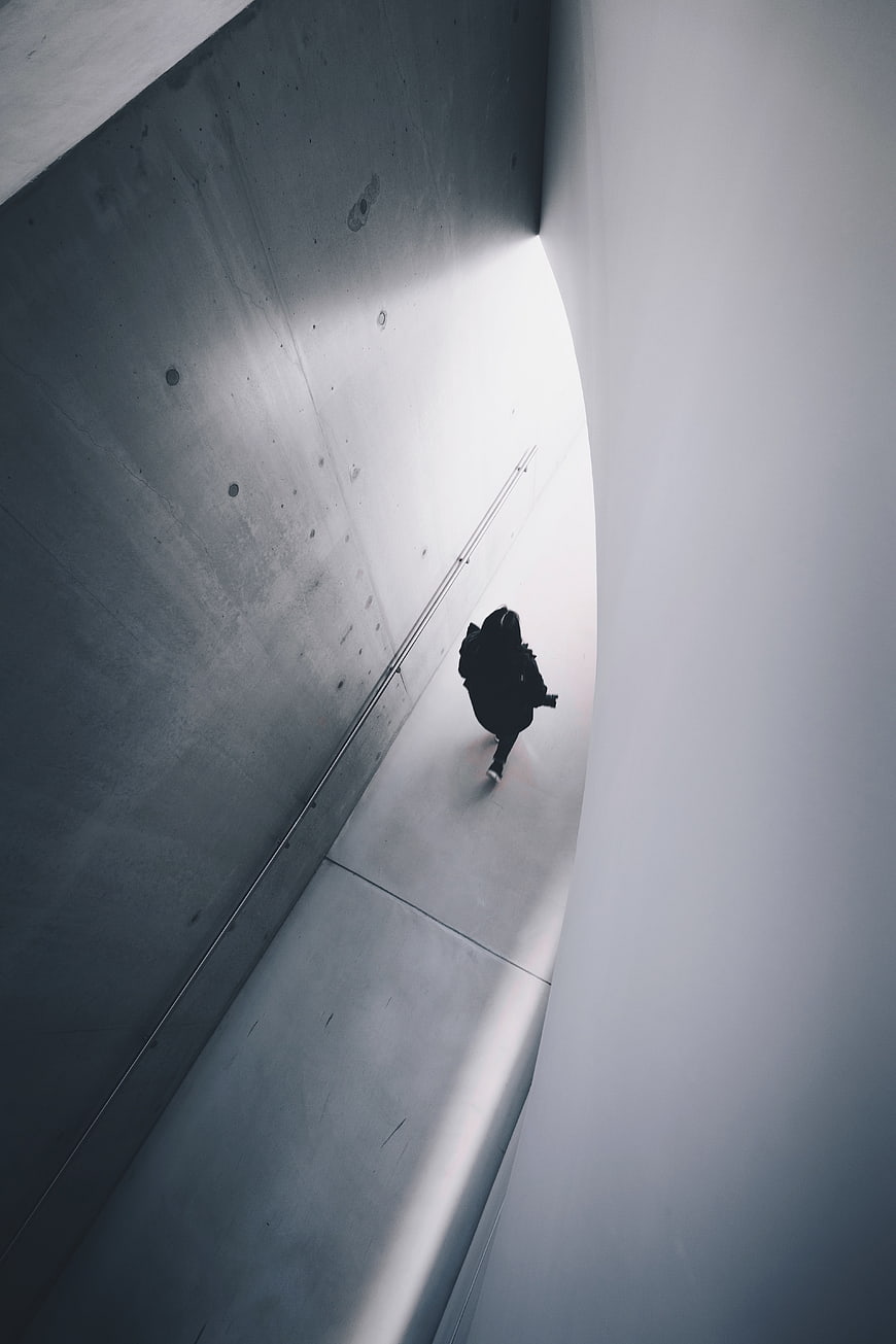 Silhouette of person walking in concrete tunnel