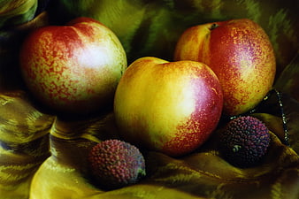 Still life of nectarines and lychees on golden fabric