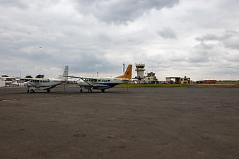 Small propeller airplanes parked on airport tarmac with control tower