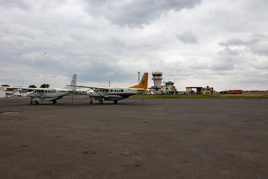 Small propeller airplanes parked on airport tarmac with control tower