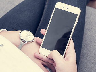 Woman holding white smartphone with blank screen and wristwatch