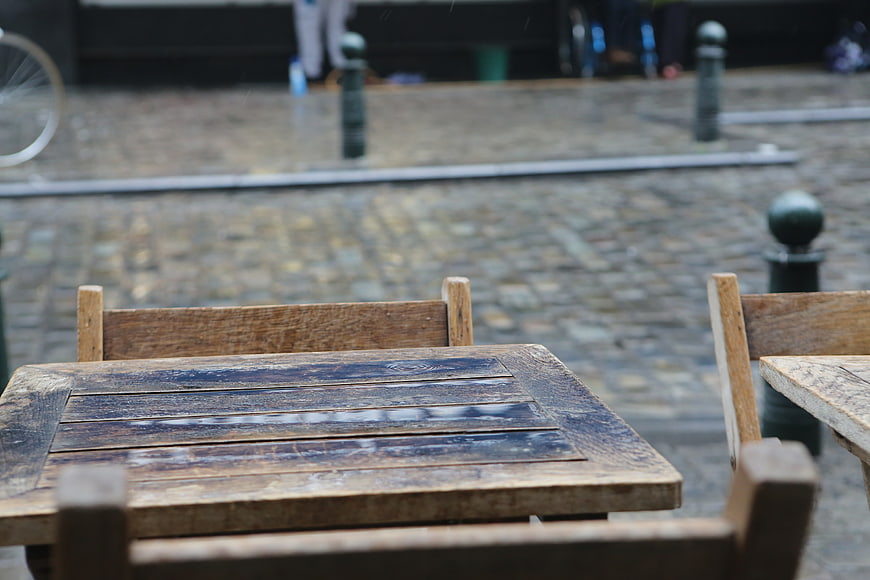 Empty wooden cafe table on rainy cobblestone street