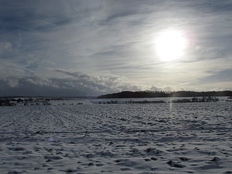 Snowy Winter Landscape with Bright Sun and Clouds
