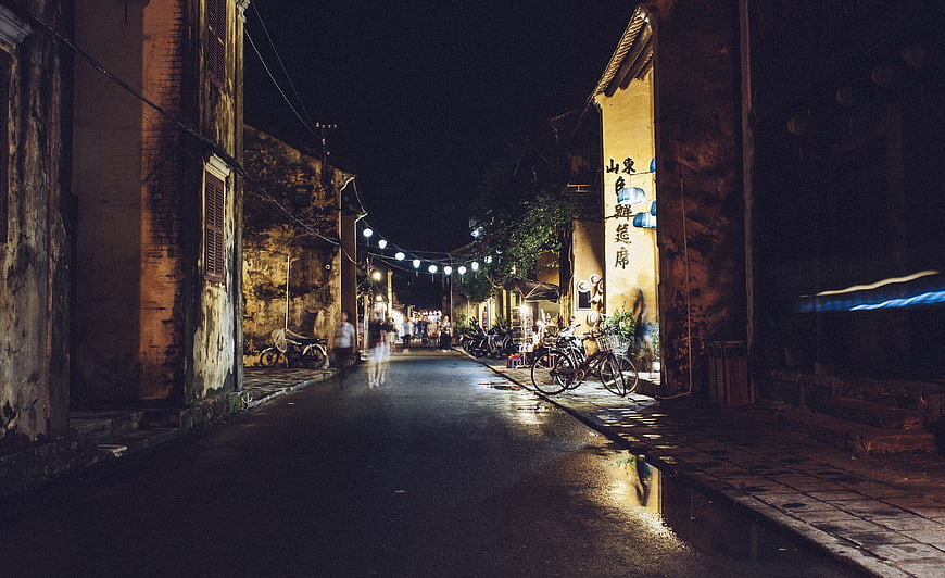 Night street scene in old Asian town with wet road and string lights