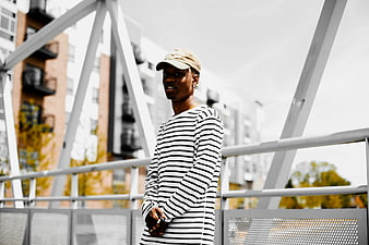 Young Black Man in Striped Shirt on Urban Bridge