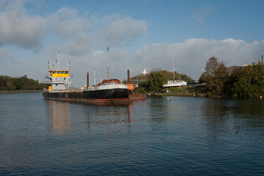 Cargo barge navigating calm river with autumn trees