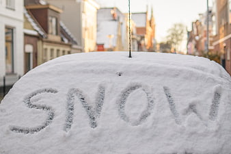 Word Snow Written on Snow-Covered Car Roof in City