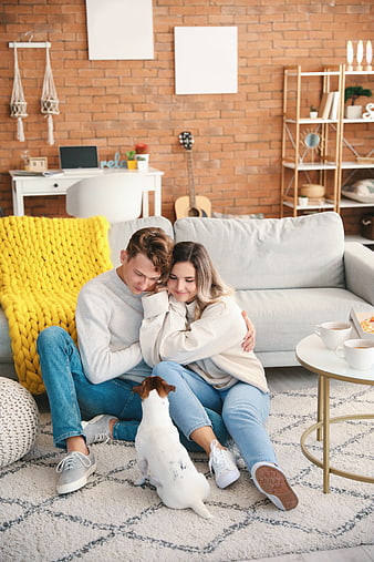 Happy young couple hugging on living room floor with dog