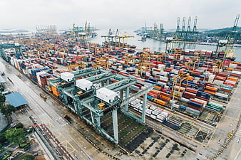 Aerial view of busy shipping port with stacked containers and cranes