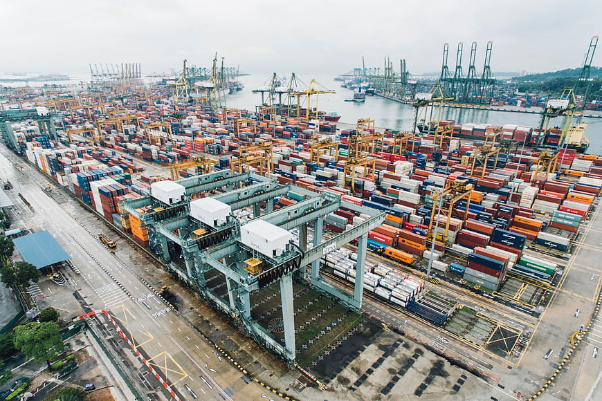 Aerial view of busy shipping port with stacked containers and cranes