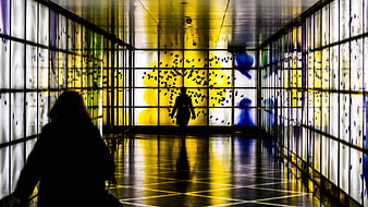 Silhouettes in a Colorful Glass Tunnel with Yellow and Blue Light