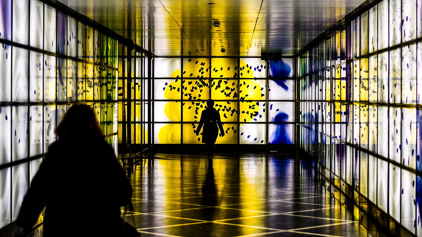 Silhouettes in a Colorful Glass Tunnel with Yellow and Blue Light