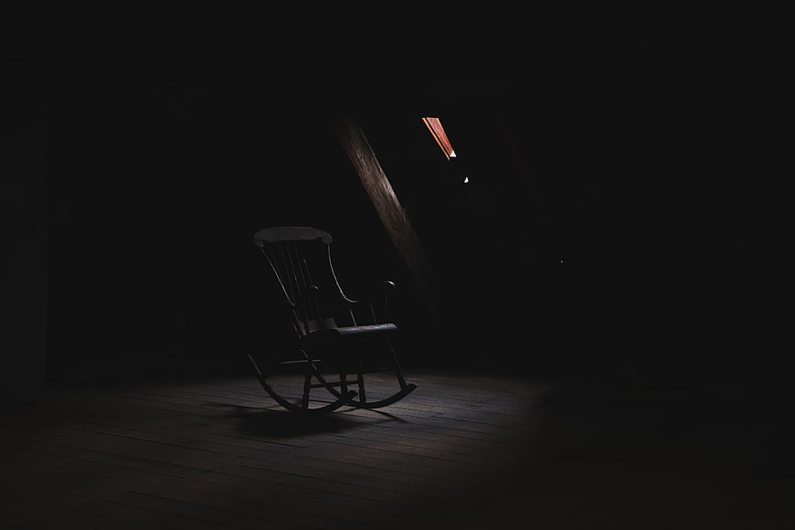 Dark moody rocking chair in dim attic room