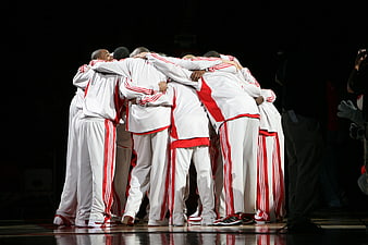 Professional basketball team huddle on court in white and red uniforms