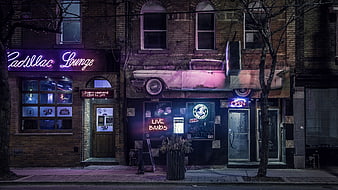 Neon-lit Cadillac Lounge bar exterior at night with vintage car mural