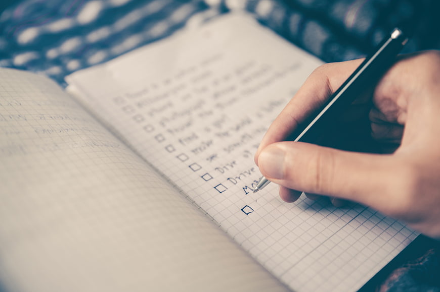 Hand writing to-do list in notebook with pen