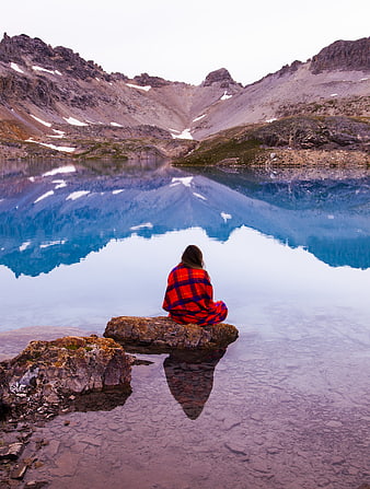 Woman in Red Plaid Blanket Sitting by Frozen Mountain Lake