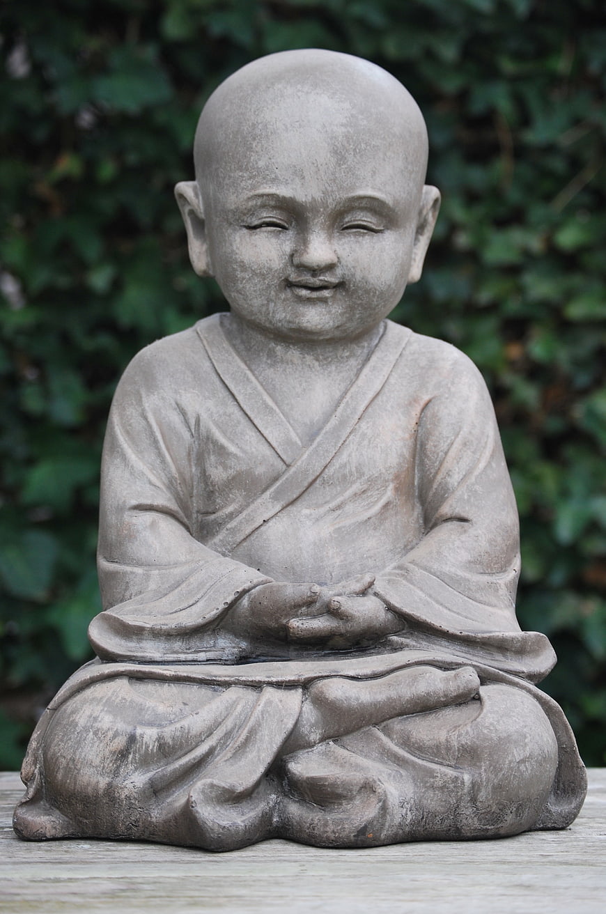 Stone statue of meditating monk in zen garden
