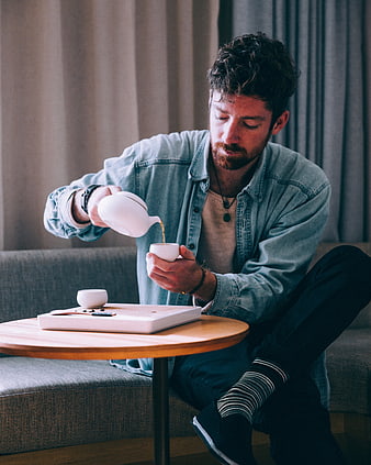 Man Pouring Tea from White Teapot into Cup