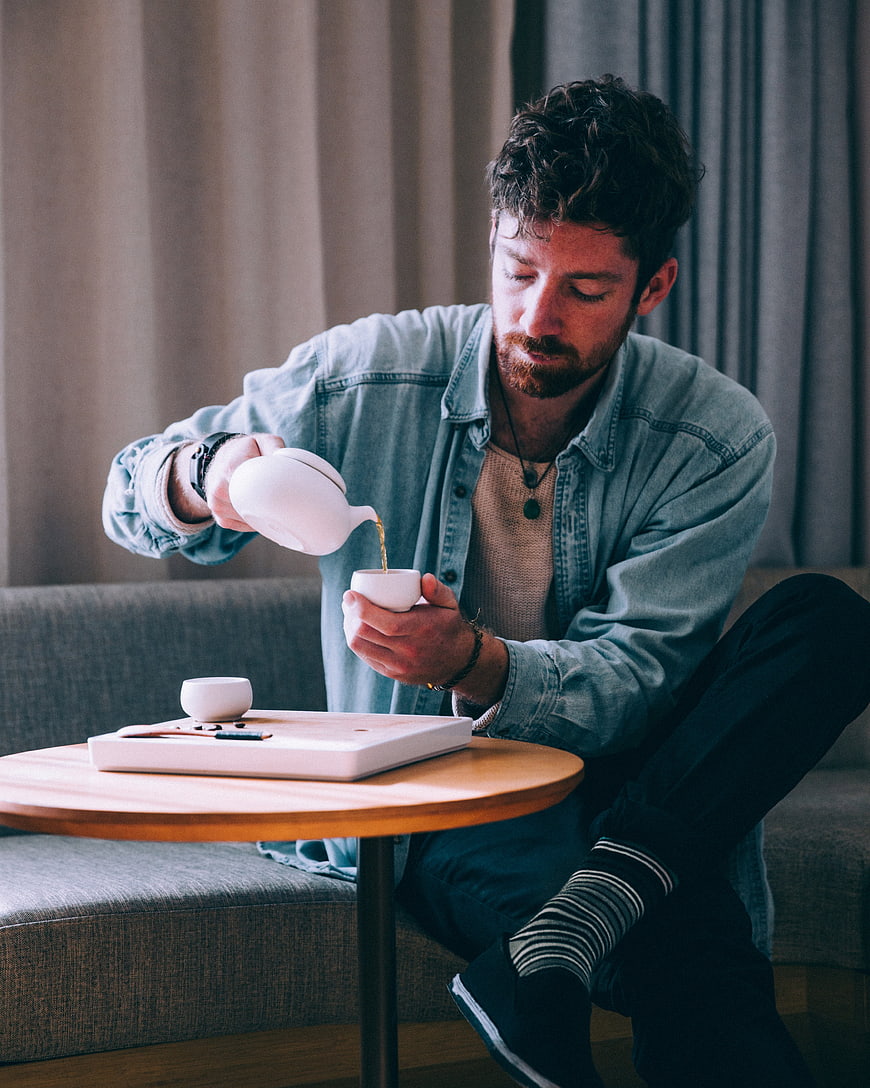 Man Pouring Tea from White Teapot into Cup