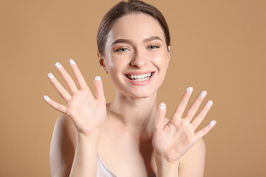 Smiling woman showing manicured hands and healthy skin