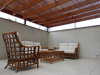 Rattan furniture set with white cushions under wooden pergola