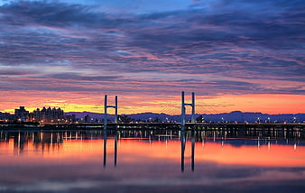 Cable-stayed bridge over calm water at vibrant sunset