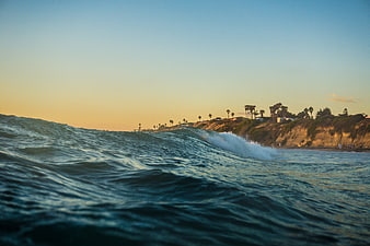 Ocean Wave Crashing Near Coastal Cliffs at Sunset