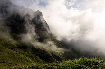 Misty green mountain landscape with fog and clouds