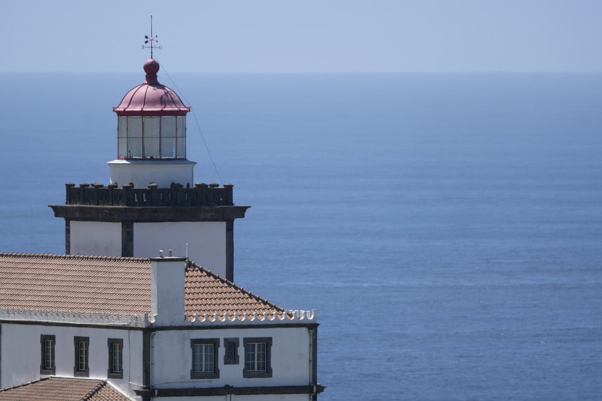White Lighthouse with Red Roof Overlooking Blue Ocean