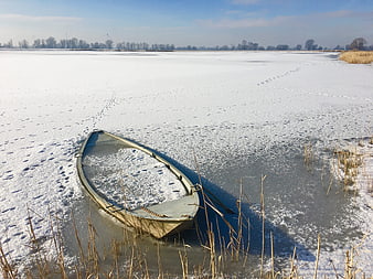 Frozen boat on icy lake in winter landscape