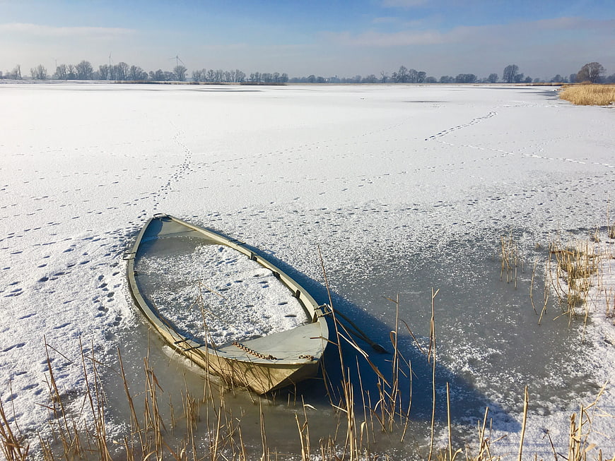 Frozen boat on icy lake in winter landscape