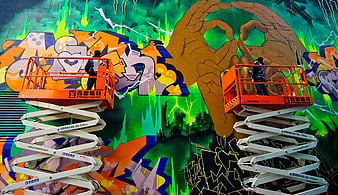 Artists painting large graffiti mural on wall