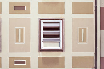 Symmetrical beige building facade with central window and geometric patterns