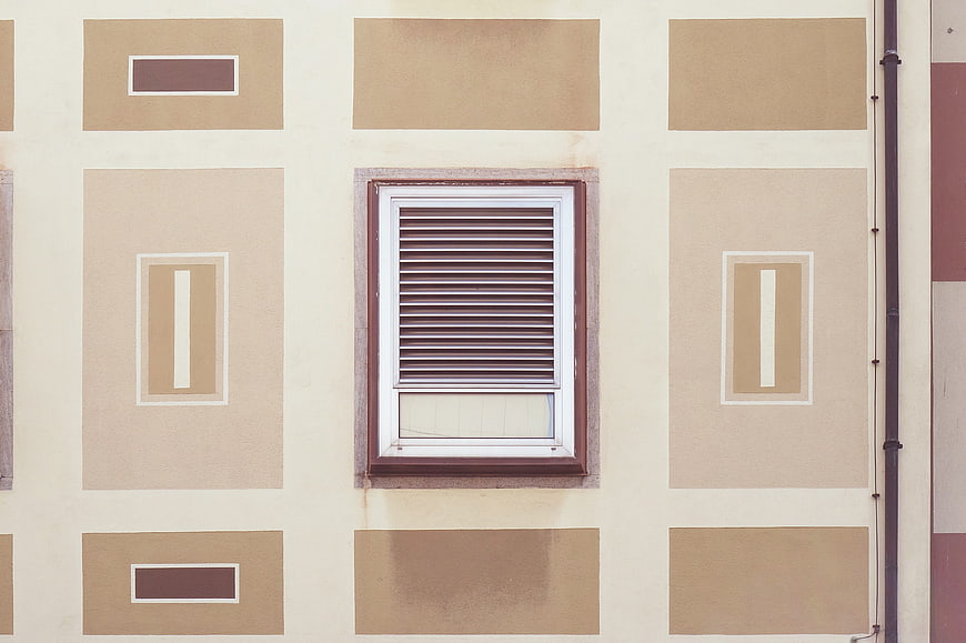 Symmetrical beige building facade with central window and geometric patterns