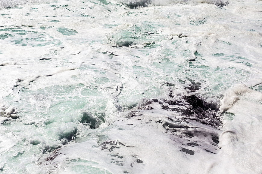 Turbulent turquoise ocean waves crashing over rocks