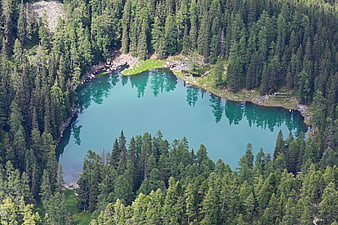 Aerial view of turquoise alpine lake surrounded by pine forest