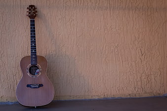 Acoustic Guitar Leaning Against Textured Stucco Wall